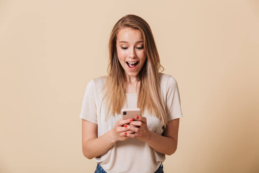 A happy woman writing in a dating app on her mobile