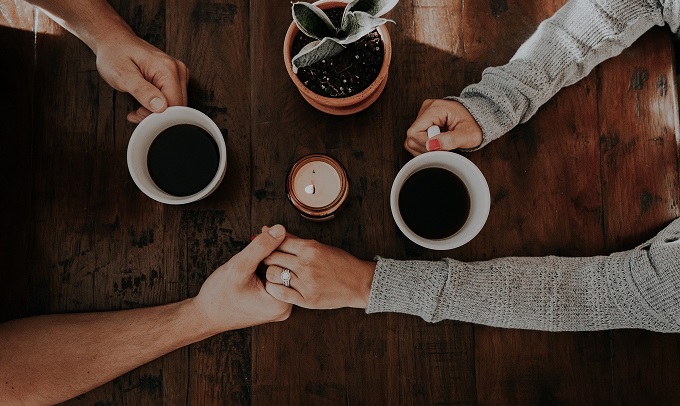 couple holding hands while drinking coffee together